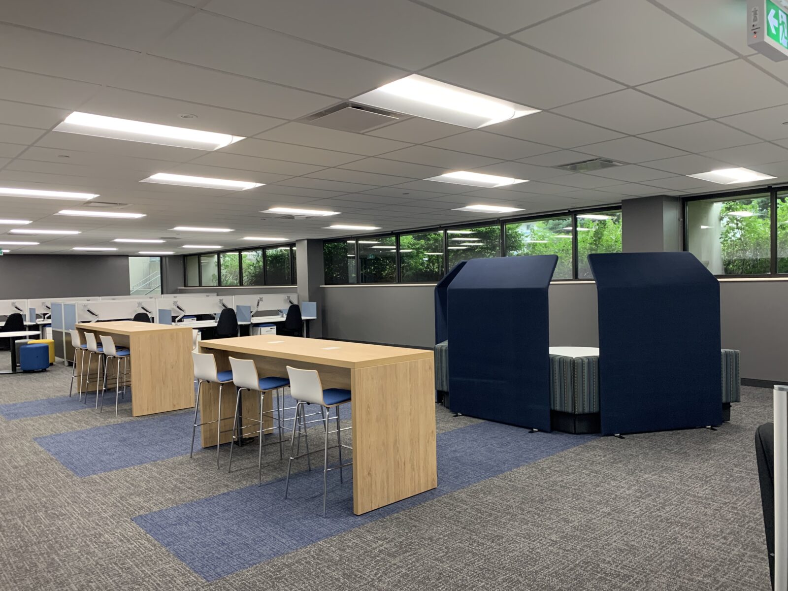 Interior office space showing bar-height collaboration spaces and individual workstations in the background